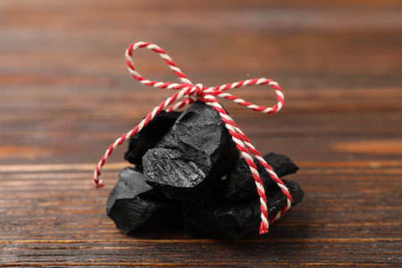 Pieces of black coal on wooden table, closeup. Christmas tradition for kidsの写真素材