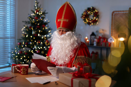 Saint Nicholas with letter at desk in room decorated for Christmasの写真素材