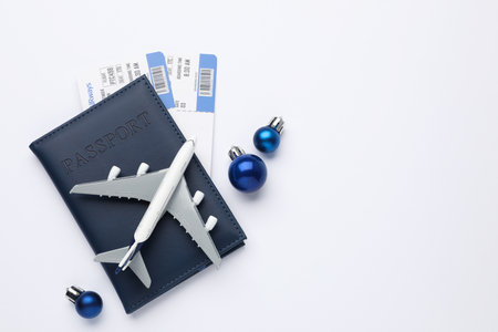 Christmas vacation. Passport with tickets, plane model and ornaments on white background, flat lay. Space for textの写真素材