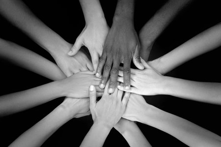 Group of people stacking their hands together, top view. Black-and-white toningの写真素材