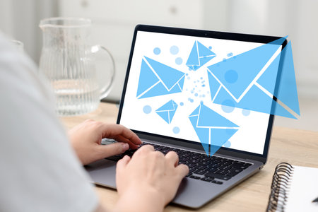 Woman sending or receiving email on laptop at table, closeup. Letters flying out of screen