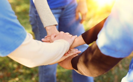 Group of volunteers stacking hands outdoors on sunny day, closeup. Banner design