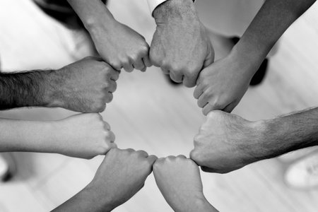 Group of people holding their fists together, top view. Black-and-white toningの写真素材