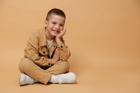 Portrait of cute little boy on beige background, space for textの写真素材