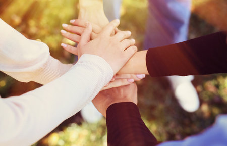 Group of volunteers stacking hands outdoors on sunny day, closeup. Banner design