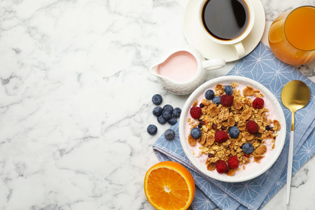 Tasty breakfast. Granola with yogurt and fruits served on white marble table, flat lay. Space for...