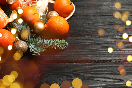 Fresh tangerines, Christmas ornaments and fir tree branches on wooden table, bokeh lightsの写真素材