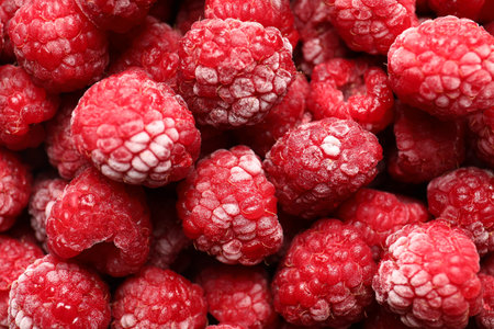 Frozen ripe raspberries as background, top view