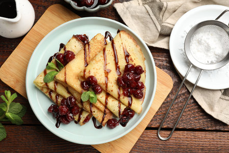 Delicious crepes served with cherry jam and chocolate on wooden table, flat layの写真素材