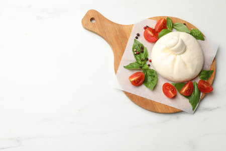 Delicious burrata cheese with tomatoes, peppercorns and basil on white marble table, top view. Space for textの写真素材