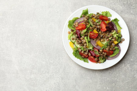 Tasty salad with lentils and vegetables on gray table, top view. Space for textの写真素材