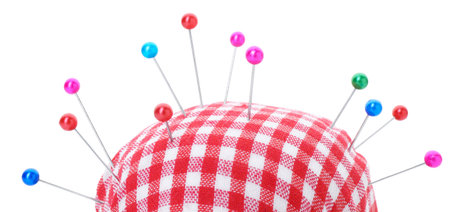 Checkered pincushion with pins on white background. Sewing accessoryの写真素材