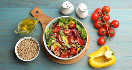 Delicious lentil salad and ingredients on light blue wooden table, flat layの写真素材