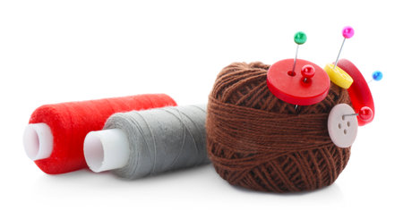 Ball of bright knitting yarn with buttons, spools of thread and pins isolated on white