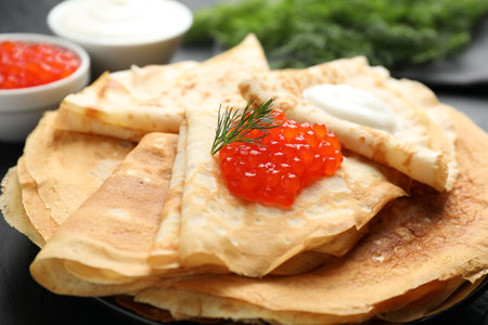 Delicious crepes with red caviar and sour cream on black table, closeupの写真素材