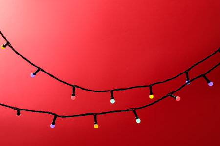 Bright Christmas lights on red background, closeup. Space for textの写真素材