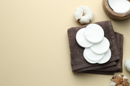 Clean cotton pads, flowers and towel on beige background, flat lay. Space for textの写真素材