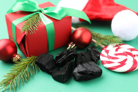 Christmas gift for kids. Pieces of black coal, festive decor and candy on green background, closeupの写真素材