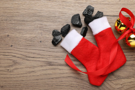 Pieces of black coal in Christmas stockings on wooden table, flat lay. Space for textの写真素材