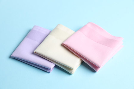 Different pastel color handkerchiefs on light blue background, closeup