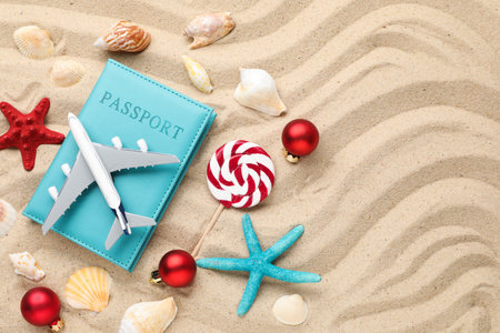 Christmas vacation. Passport, plane model, shells, lollipop and ornaments on beach, flat lay. Space for textの写真素材