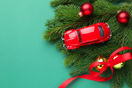 Christmas vacation. Toy car, fir branches and ornaments on turquoise background, flat lay. Space for textの写真素材