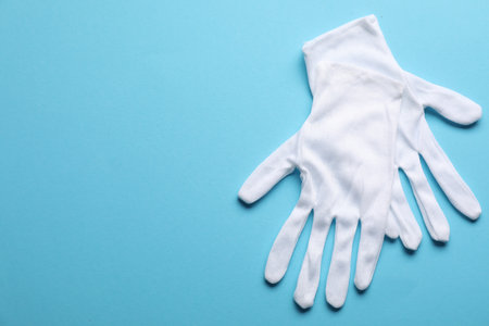 Pair of white cloth gloves on light blue background, top view. Space for textの写真素材