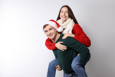 Smiling couple having fun on light background, space for text. Merry Christmas and Happy New Yearの写真素材
