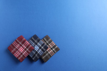 Different stylish fabric handkerchiefs on blue background, flat lay. Space for textの写真素材