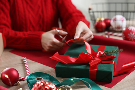 Woman wrapping Christmas gift at wooden table, closeupの写真素材