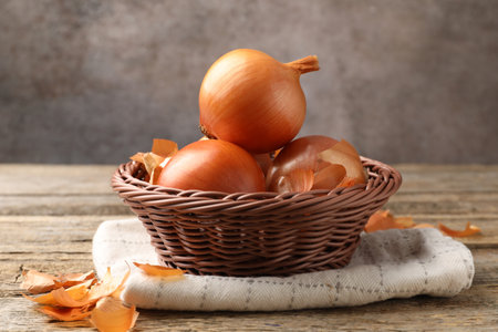Fresh onion bulbs and peels on wooden table, closeupの写真素材