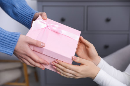 Merry Christmas and Happy New Year. Woman giving gift box to her friend indoors, closeupの写真素材