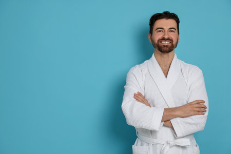 Man in bathrobe on light blue background. Space for textの写真素材