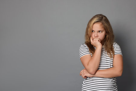 Portrait of cute girl on gray background, space for text