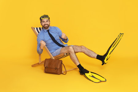 Businessman with diving mask and flippers in deck chairの写真素材