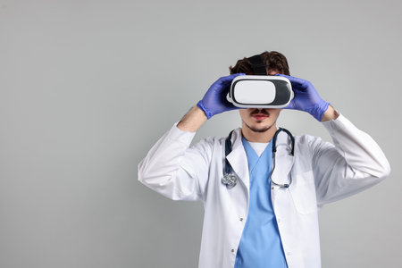 Modern technology. Doctor using virtual reality headset on gray background. Space for textの写真素材