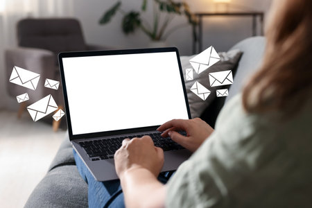 Woman sending or receiving email on laptop at home, closeup. Letters flying out of screenの写真素材