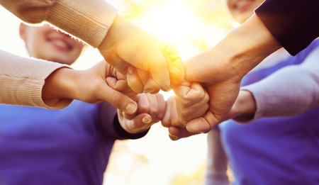 Group of volunteers bumping fists outdoors on sunny day, closeup. Banner designの写真素材