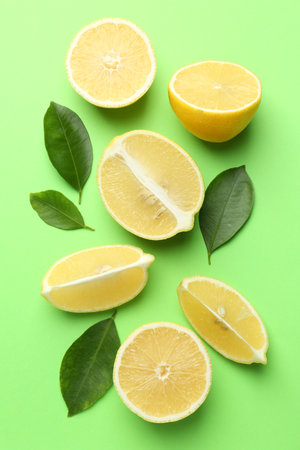 Fresh ripe lemons and leaves on light green background, flat layの写真素材