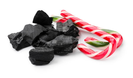 Pieces of black coal and candy canes on white backgroundの写真素材