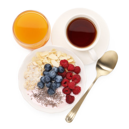 Healthy breakfast. Oatmeal with nuts, berries, yoghurt, tea and juice isolated on white, top viewの写真素材