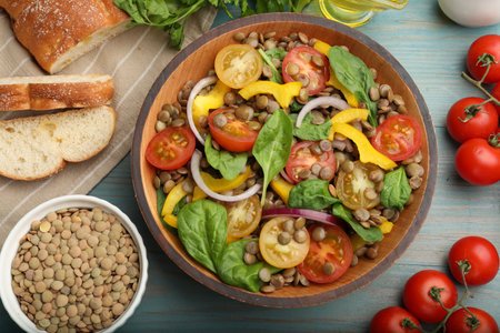 Tasty lentil salad, ingredients and bread on light blue wooden table, flat layの写真素材