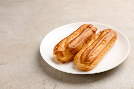 Fresh tasty eclairs on light table, closeup. Space for text