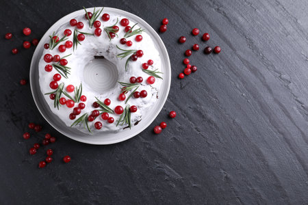 Tasty Christmas cake with cranberries and rosemary on dark textured table, flat lay. Space for textの写真素材
