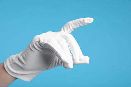 Woman in cloth glove on light blue background, closeupの写真素材