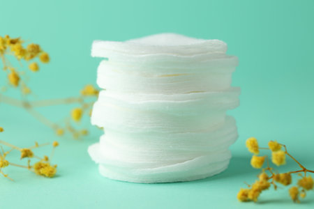 Stack of clean cotton pads and flowers on turquoise background, closeupの写真素材