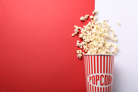 Tasty popcorn in paper cup on color background, top view. Space for textの写真素材