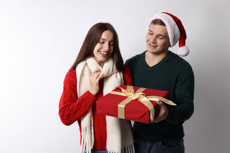 Happy couple with Christmas gift on light backgroundの写真素材