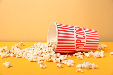 Popcorn in paper cup on orange table against beige background, closeupの写真素材