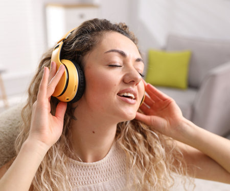 Happy woman in headphones listening music at homeの写真素材